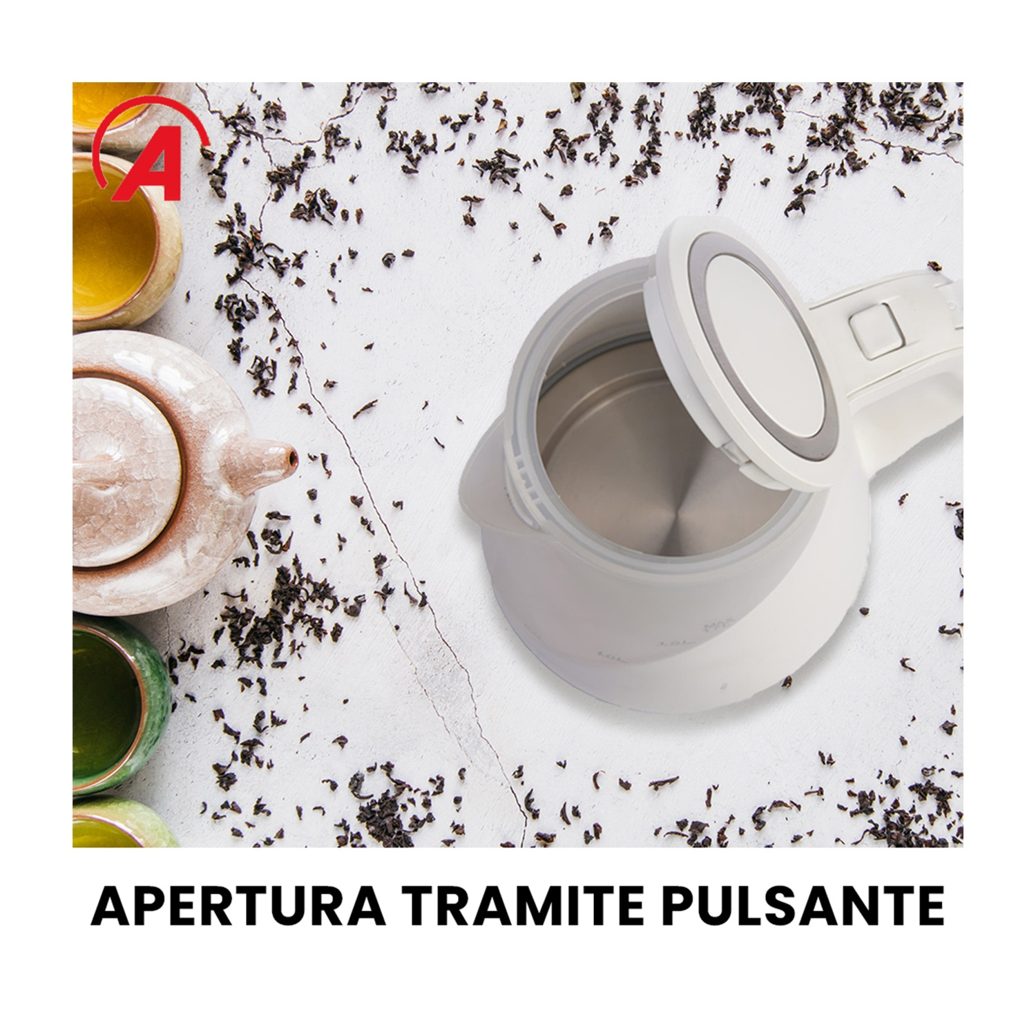 Bollitore elettrico bianco con coperchio aperto, foglie di tè sparse, tazze e teiera su una superficie bianca.