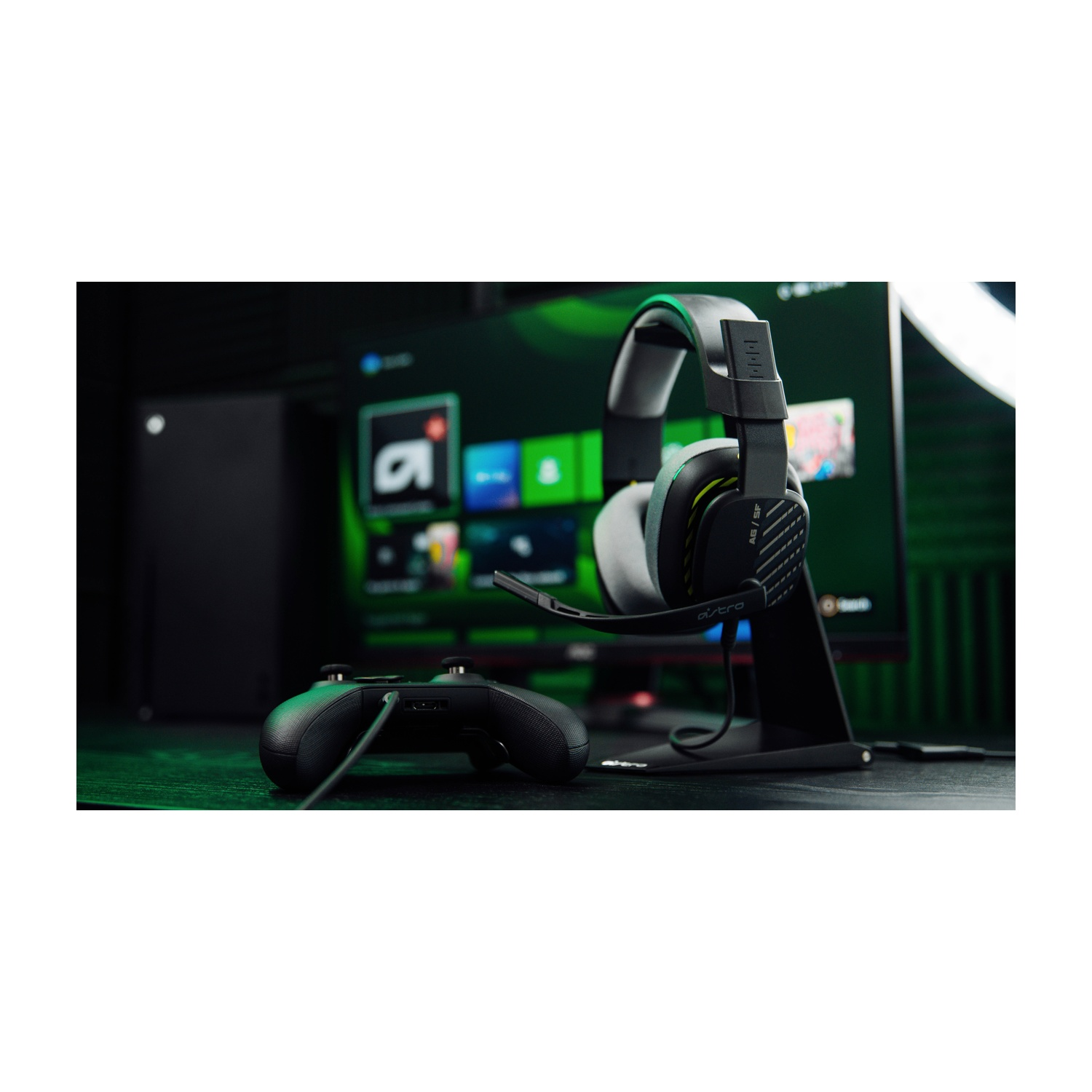 Configurazione di gioco con cuffie su supporto, controller e monitor che mostra un'interfaccia di gioco.