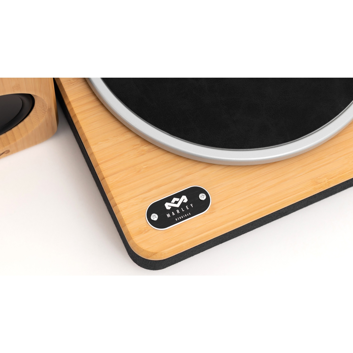 Close-up van een platenspeler. Het heeft een houten basis met een zwart midden en een zilveren rand. Links een luidspreker.