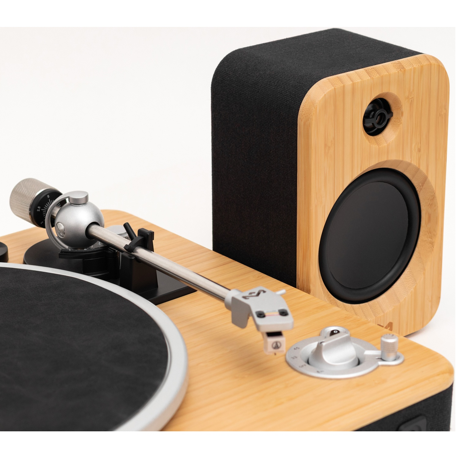 Un ensemble platine et haut-parleur. La platine a un disque vinyle noir et un bras argenté. Le haut-parleur est en bambou avec un haut-parleur noir.