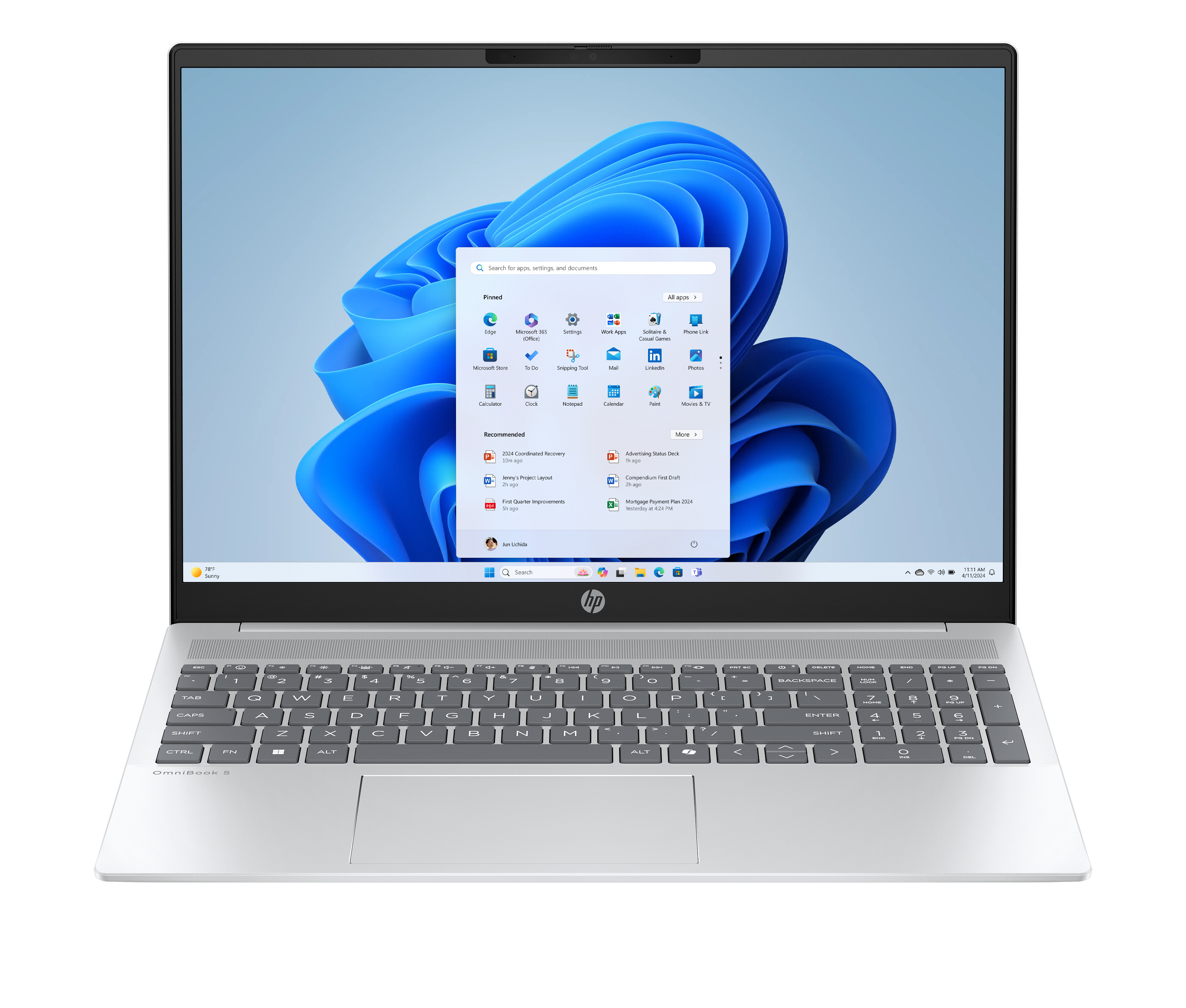 Laptop z pulpitem Windows 11. Ekran wyświetla ikony aplikacji, pasek wyszukiwania i niebieskie, abstrakcyjne tło.