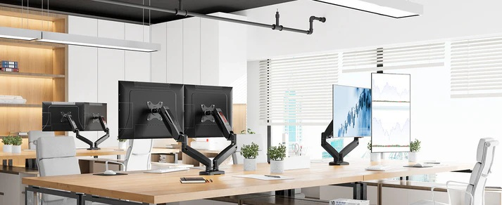 Biuro z kilkoma biurkami, z których każde ma monitory komputerowe. Monitory wyświetlają wykresy. Białe ściany i żaluzje w tle.