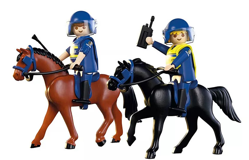 Zwei Spielzeugpolizisten auf Pferden. Ein braunes Pferd, ein schwarzes. Beide Beamte tragen Helme und blaue Uniformen.