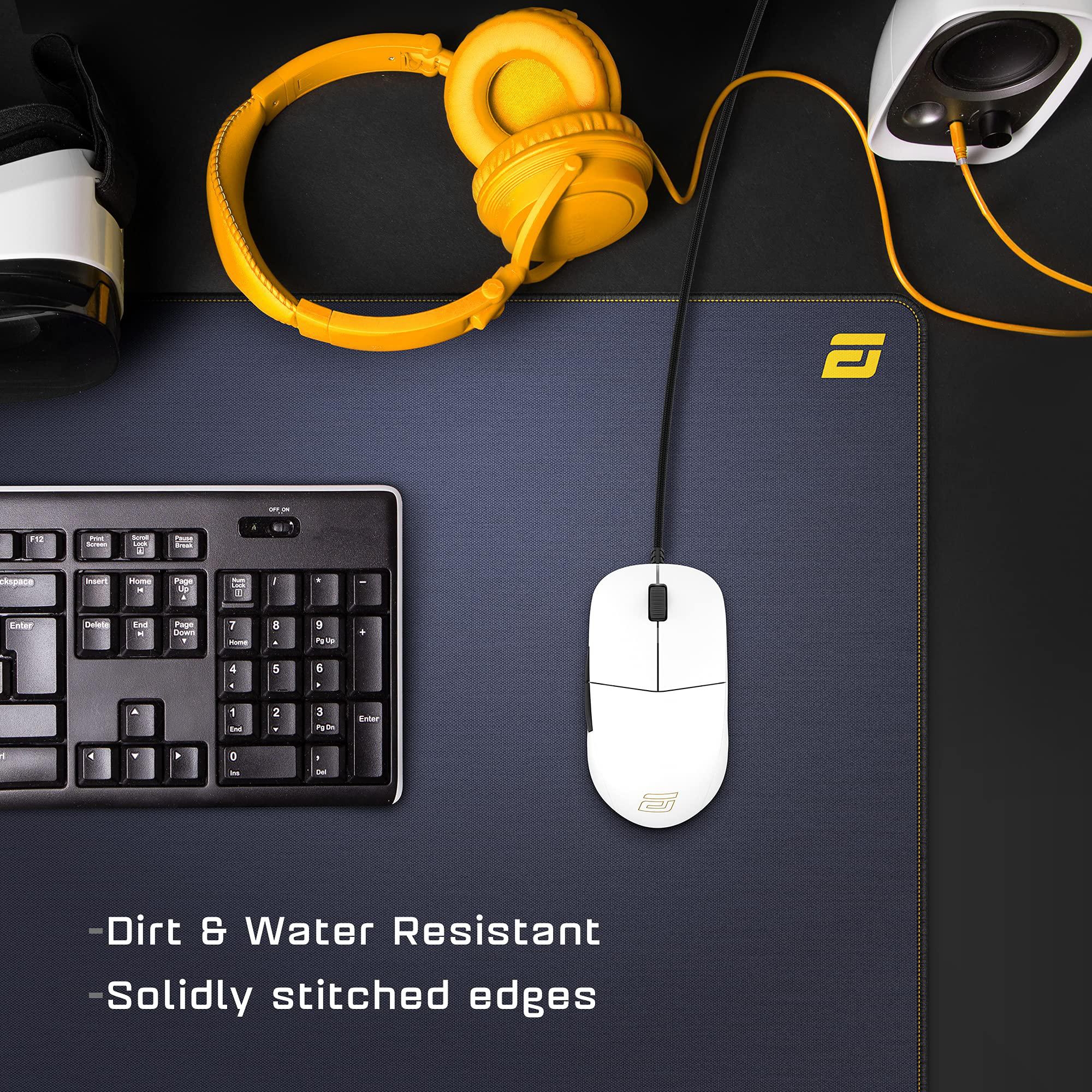 Schreibtisch-Setup mit Kopfhörern, Maus, Tastatur und Lautsprecher. Der Schreibtisch hat ein Mauspad und ist schwarz. Schmutz- und wasserabweisend.