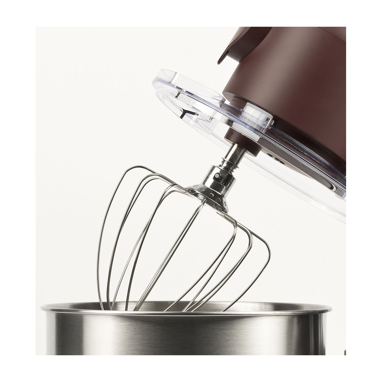Primo piano di un mixer da cucina con accessorio frusta. Il mixer è marrone e argento, con una ciotola in acciaio inossidabile. Coperchio trasparente.
