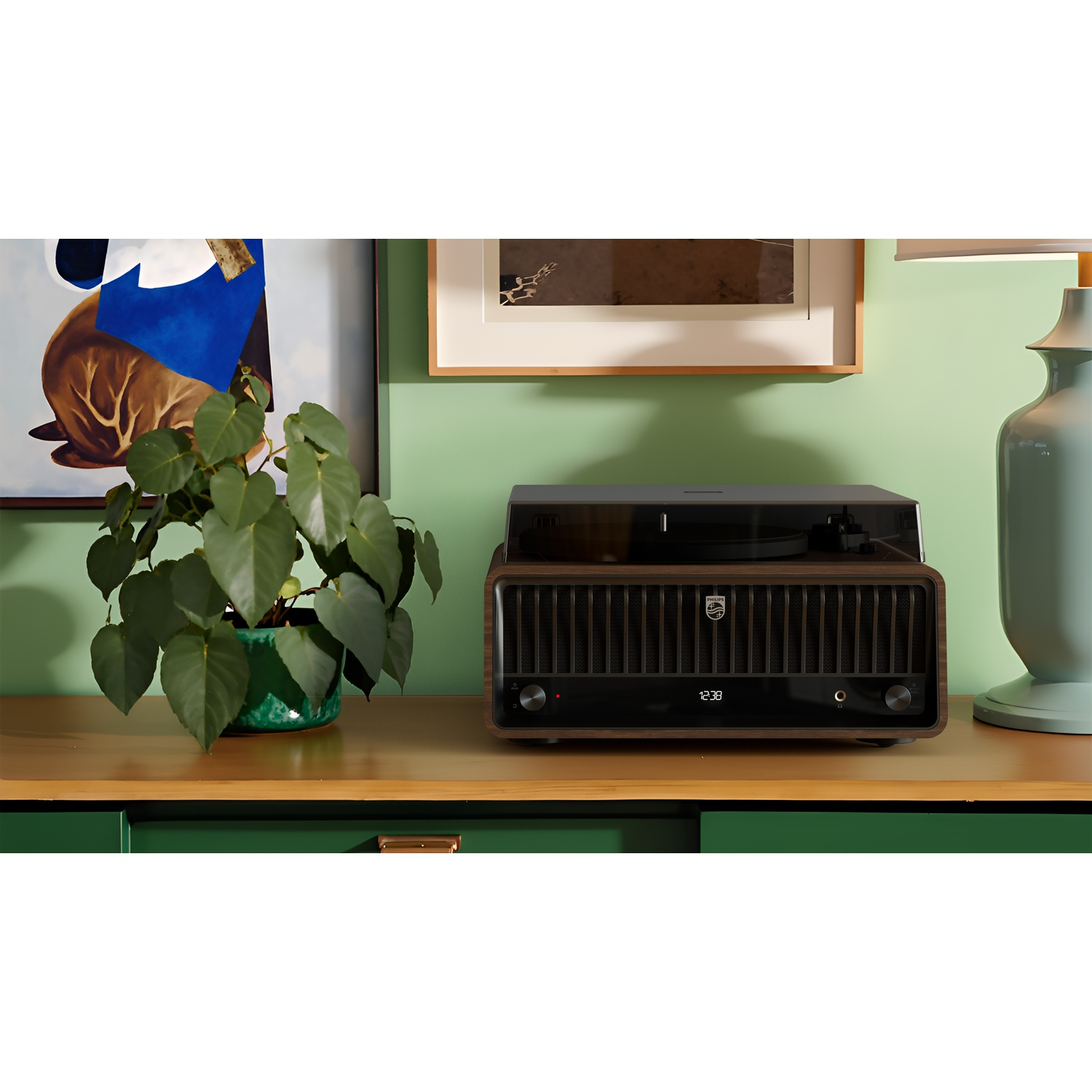Un impianto stereo in legno è su un mobile. Una pianta in un vaso verde è sul mobile. Dipinti e una lampada sullo sfondo.