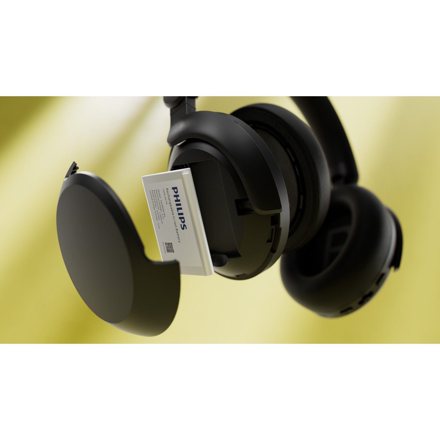 Cuffie Philips nere con scomparto aperto che rivela una batteria. La batteria ha testo, dettagli su sfondo giallo.