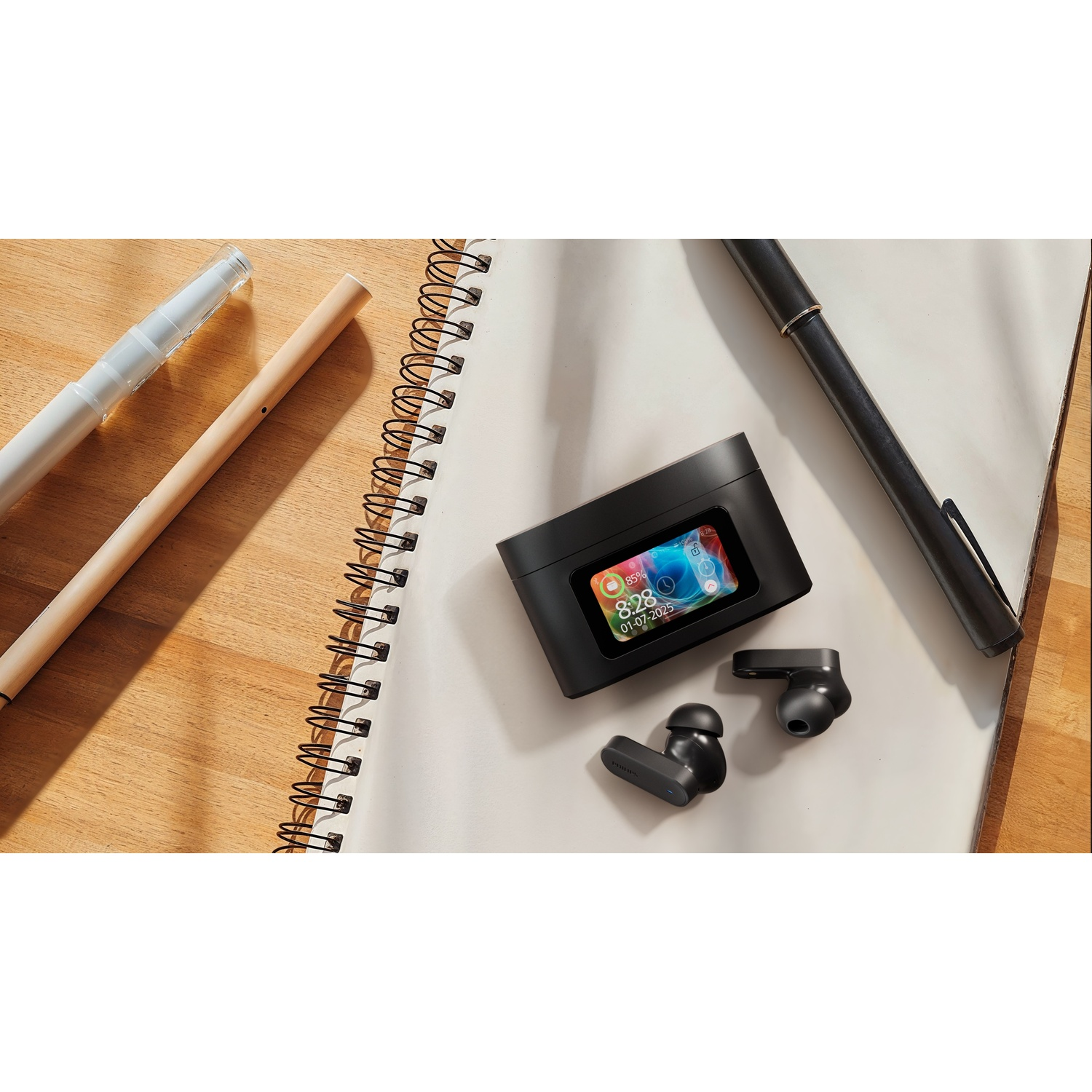 Dispositivo audio nero, auricolari e penna su un taccuino. Sfondo in legno con matita e penna bianca.