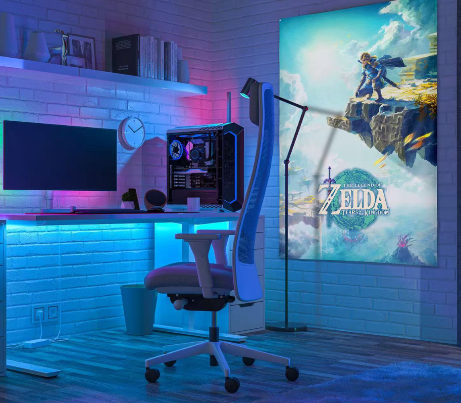 Gaming-Setup mit Computer, Stuhl und Zelda Tears of the Kingdom-Poster. Blaue und violette Beleuchtung erzeugt ein cooles Ambiente.