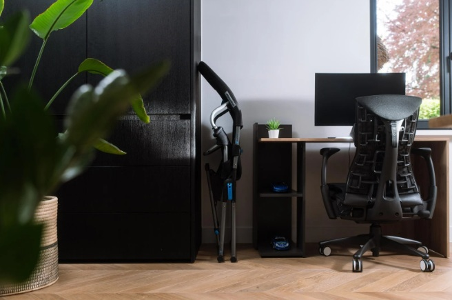 Krzesło biurowe przed biurkiem z monitorem i małą półką.