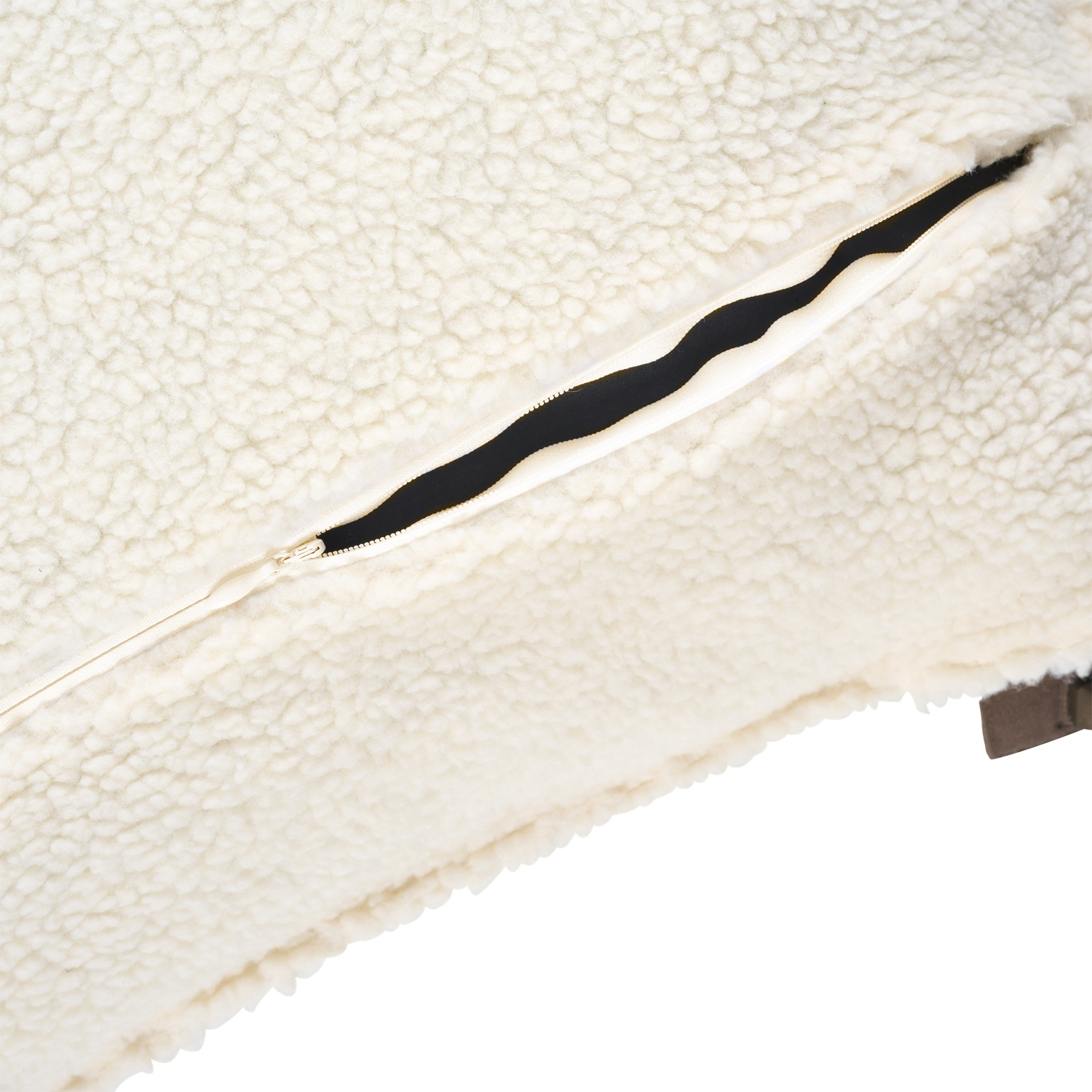 Gros plan d'un coussin crème et moelleux avec une fermeture éclair noire. Le tissu a un aspect texturé de peau de mouton.