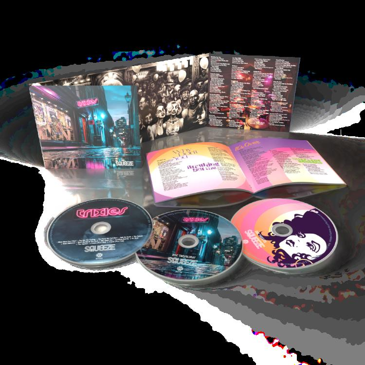 CD-Album mit drei Discs und Booklet. Das Albumcover zeigt eine Stadt bei Nacht. Andere Discs haben farbenfrohe Grafiken und Text.