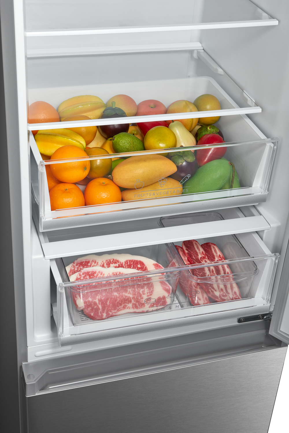 Refrigerador abierto con frutas y carne. El cajón superior tiene frutas, naranjas, mangos y pimientos. El cajón inferior tiene filetes y costillas.