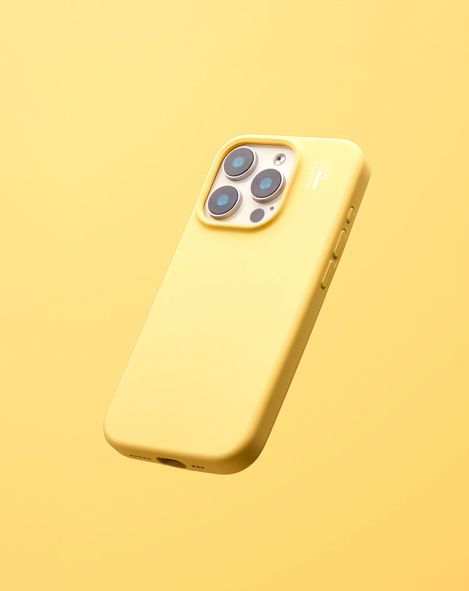 Egy sárga iPhone sárga tokban lebeg. A telefonnak három lencséje van. A háttér sárga.