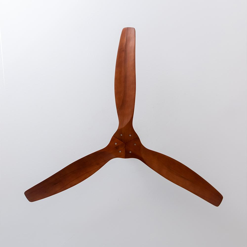 Un ventilador de techo de madera con tres aspas sobre un fondo blanco. Las aspas son de color marrón intenso.
