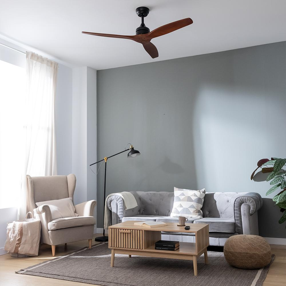 Salón con sofá, sillón, mesa de centro, alfombra y ventilador de techo. Predominan los tonos grises y beige. Hay una planta en la esquina.