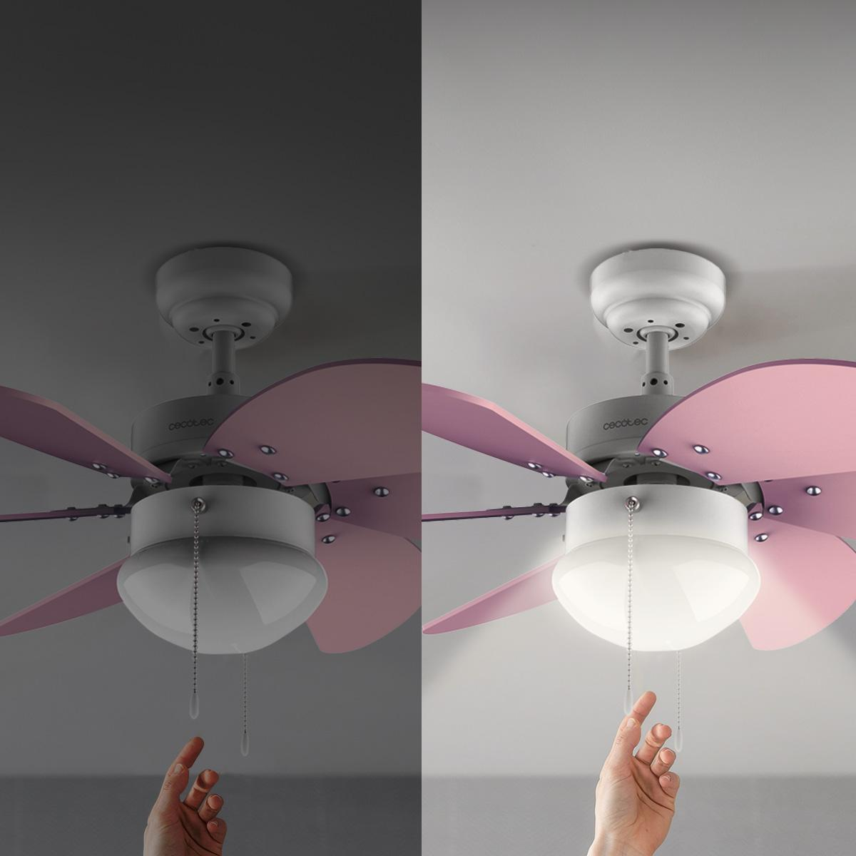 Una mano tira de una cadena para encender un ventilador de techo con aspas rosas y una luz. El ventilador está montado en un techo blanco.