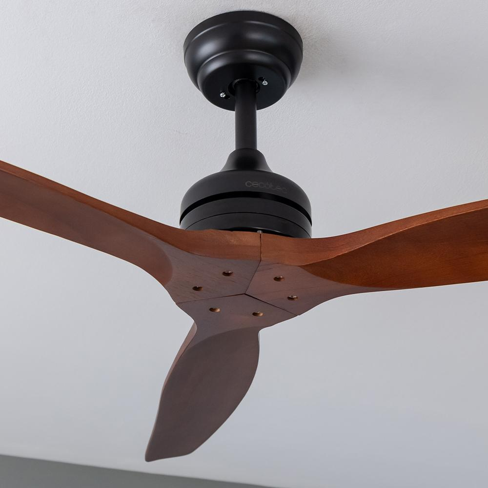 Un ventilador de techo con tres aspas de madera y una carcasa de motor negra. El ventilador está montado en un techo blanco. La marca "cecotec" es visible.