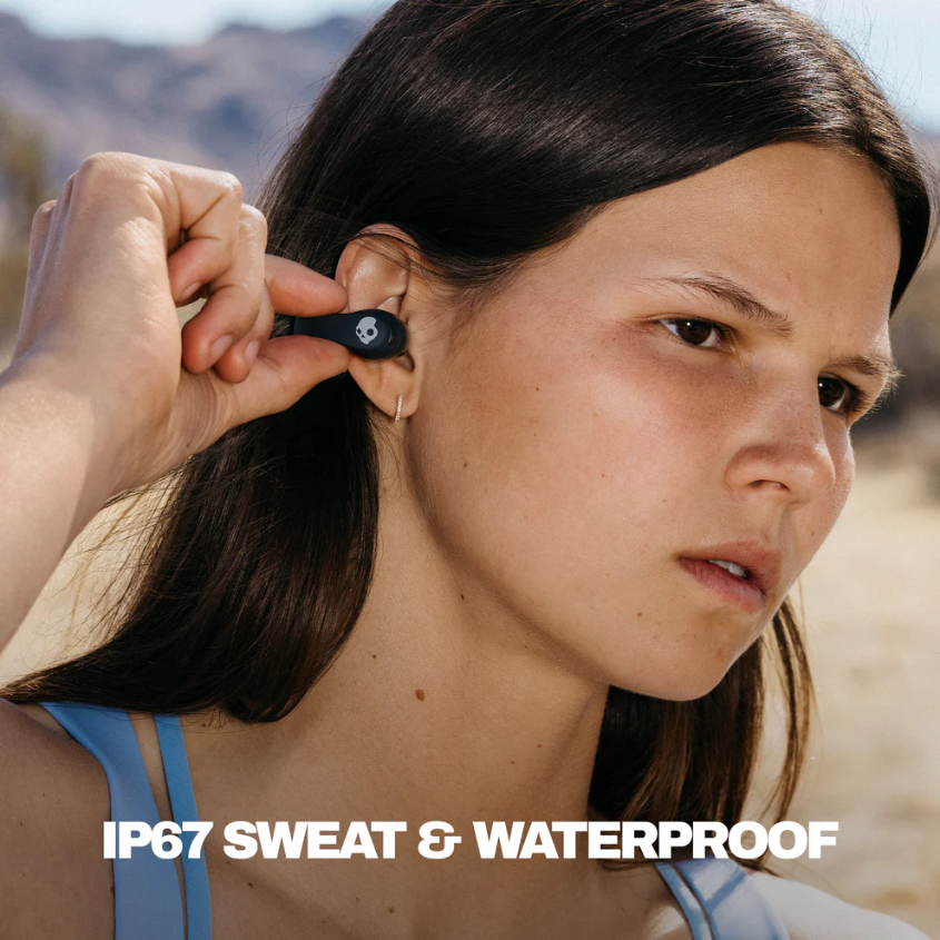 Eine Frau setzt einen schwarzen Ohrhörer mit Totenkopf-Logo ein. Der Text unten lautet IP67 SWEAT & WATERPROOF.