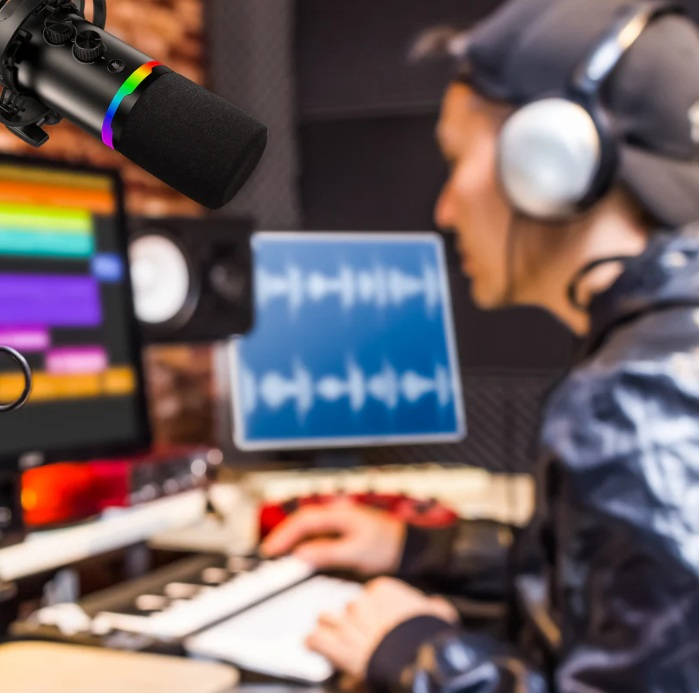 Ustawienie studia z mikrofonem, osobą w słuchawkach i komputerem wyświetlającym przebiegi audio.