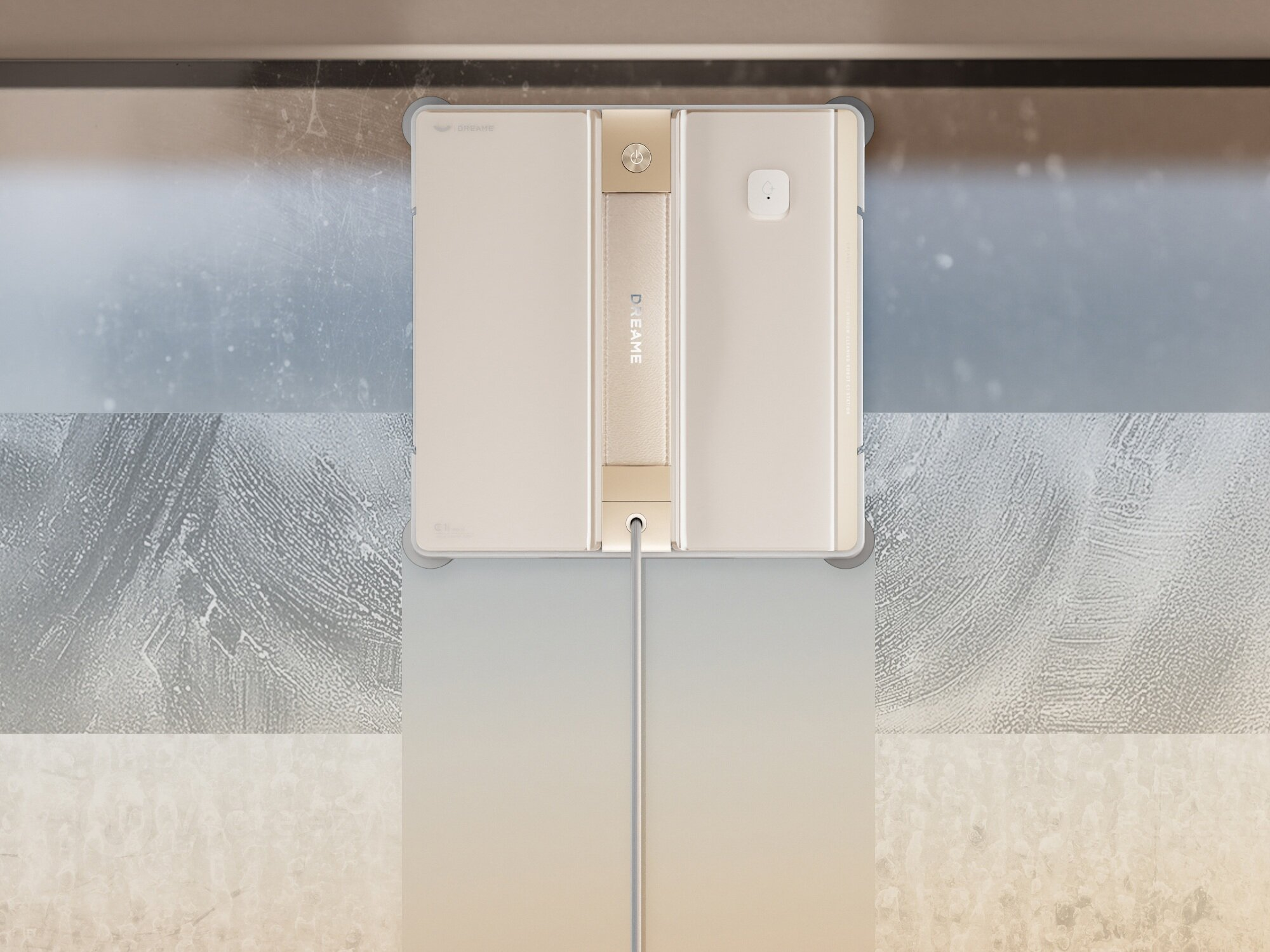 Robot do czyszczenia okien na oknie ze śladami czyszczenia. Robot jest beżowy, ze złotym uchwytem i kablem.