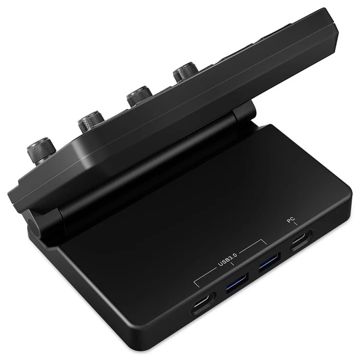 Czarne urządzenie do sterowania dźwiękiem z pokrętłami i portami USB. Ma pochyloną górną część. Baza ma porty USB 3.0 i PC.