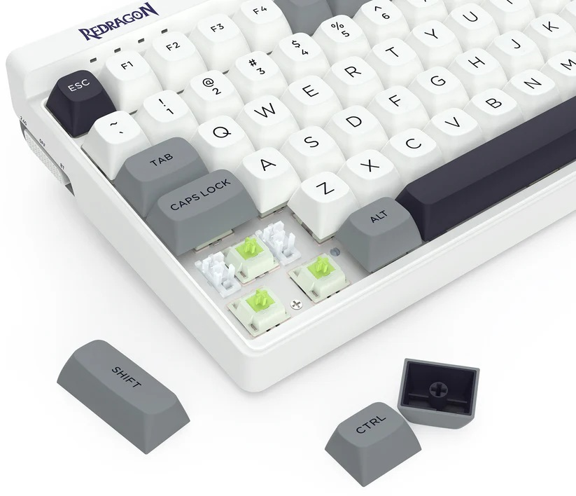 Biała klawiatura mechaniczna z szarymi i białymi klawiszami. Kilka klawiszy jest usuniętych, ukazując zielone przełączniki.
