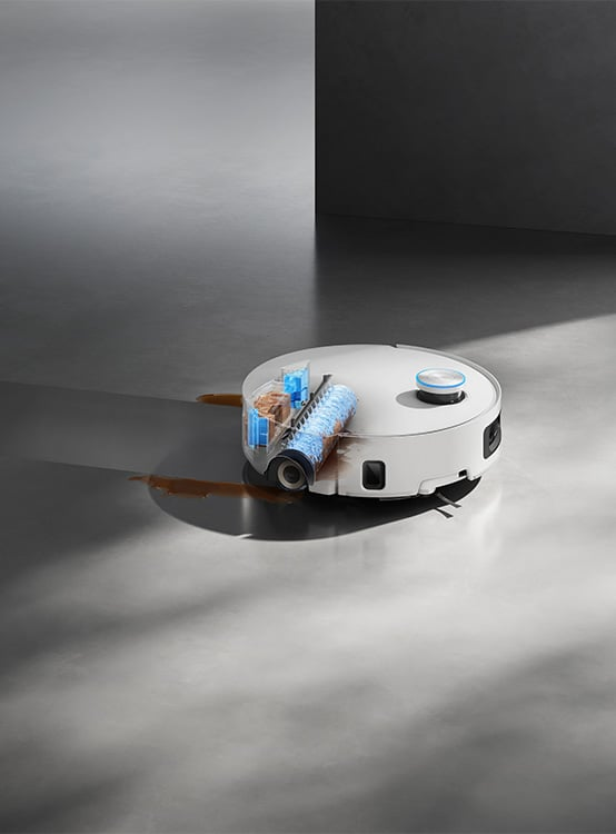 Biały robot odkurzający czyści szarą podłogę. Ma niebiesko-brązowy mechanizm czyszczący i pozostawia brązowy ślad.