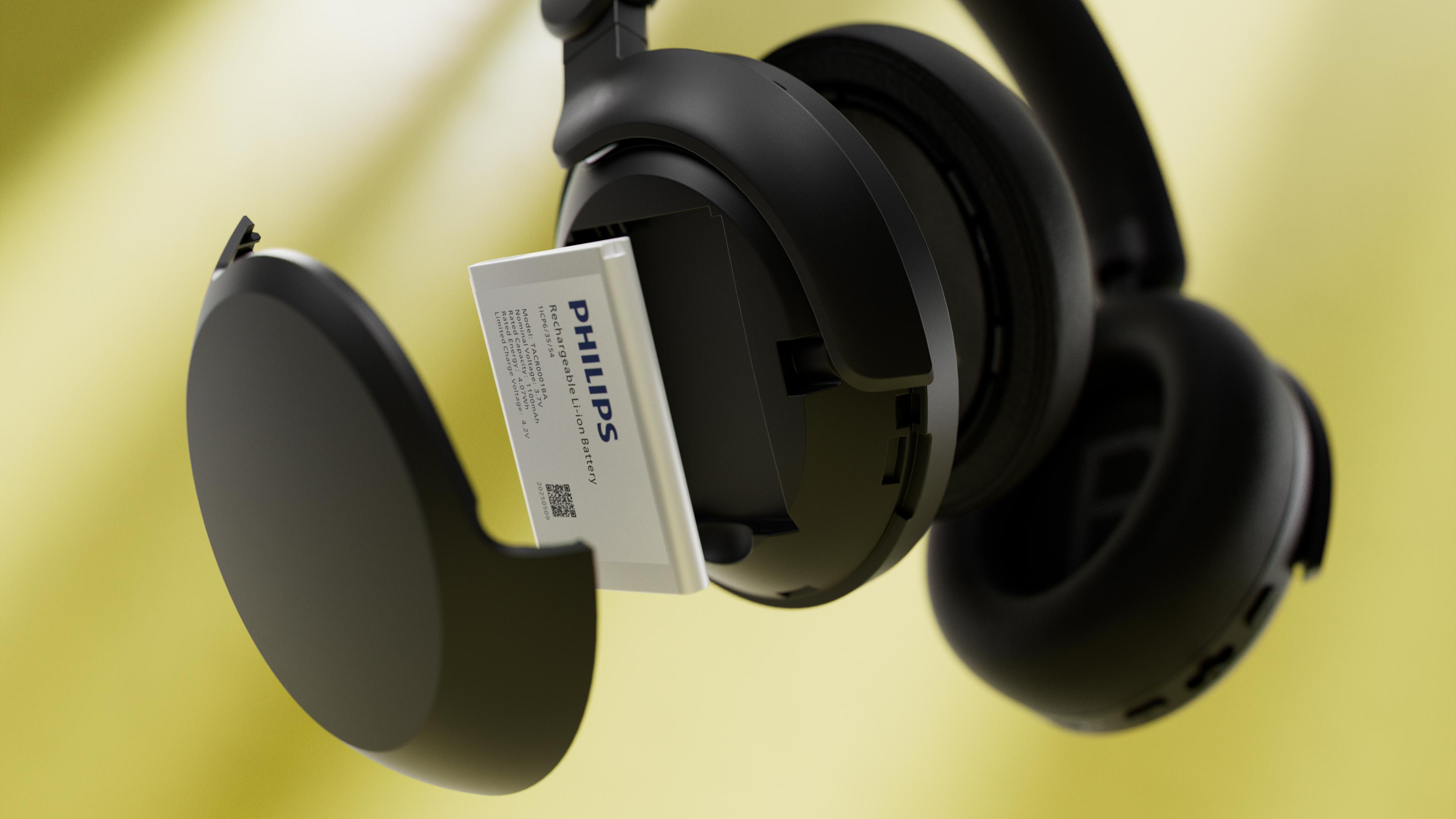 Schwarze Kopfhörer mit offenem Fach, das einen wiederaufladbaren Philips-Akku enthält, vor gelbem Hintergrund.