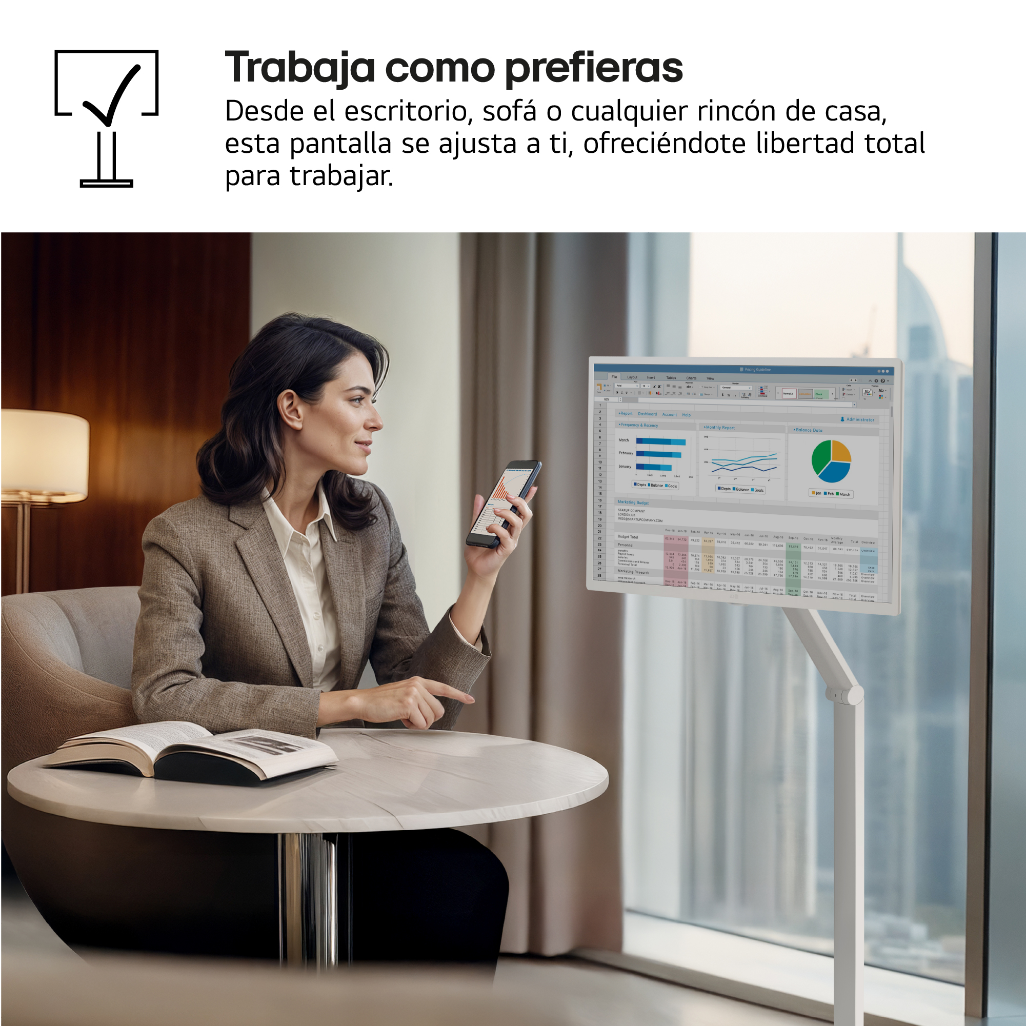 Mujer con blazer sostiene un teléfono, mirando una pantalla con gráficos. Un monitor muestra datos. Libro en la mesa.