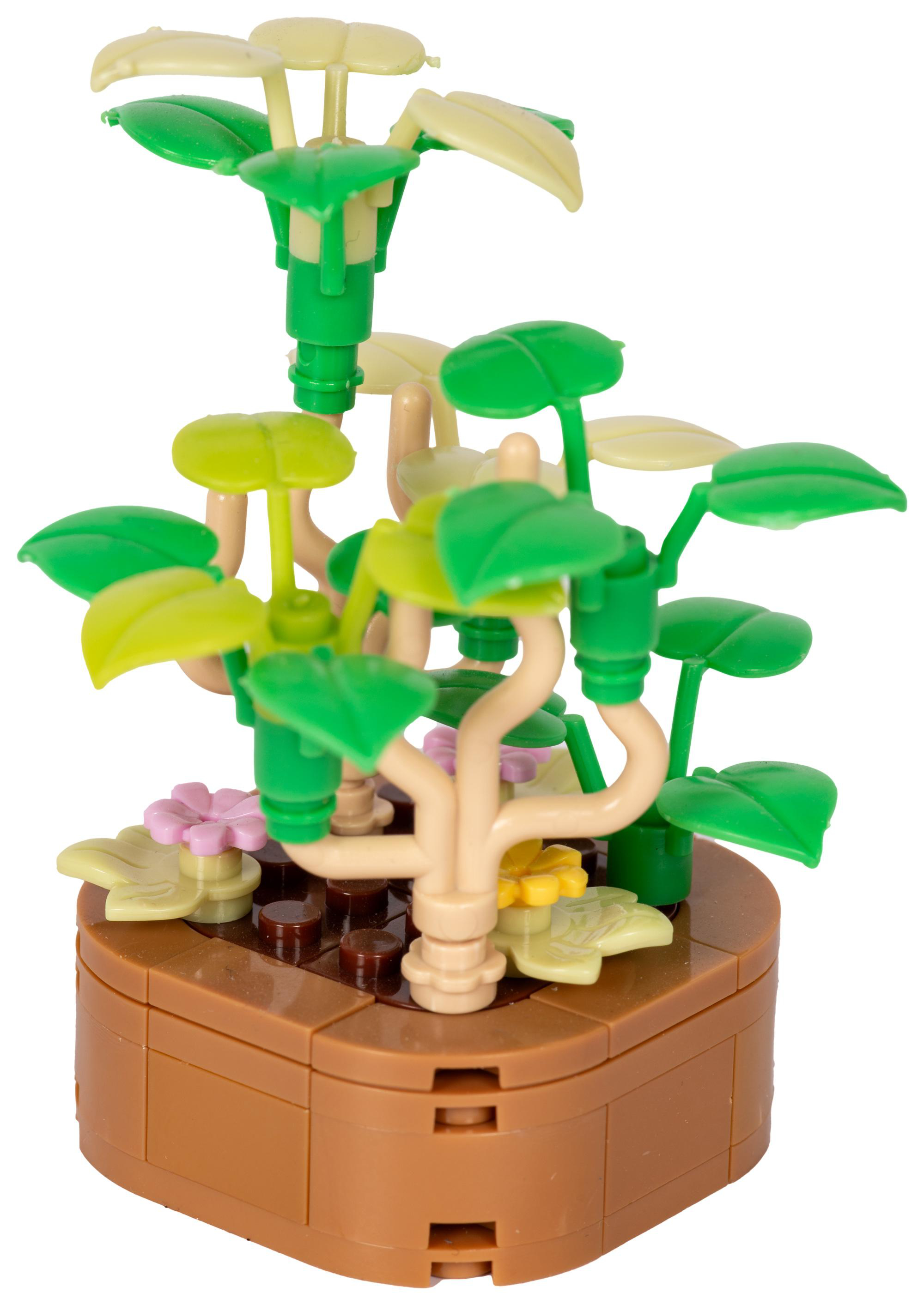 Eine Lego-Pflanze mit grünen Blättern, hellgrünen Blättern und rosa und gelben Blüten in einem braunen Topf. Weißer Hintergrund.