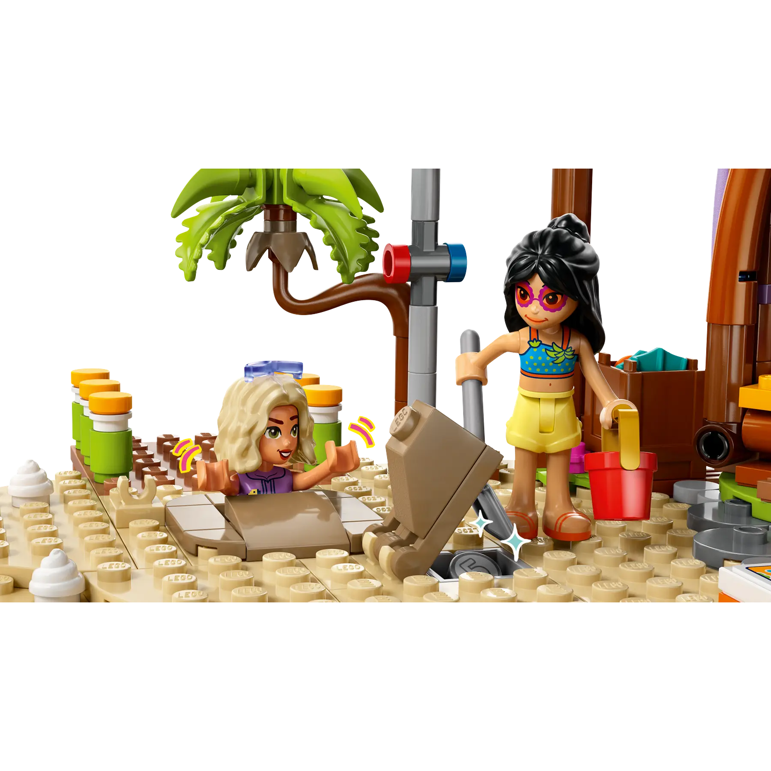 Two Lego figures on a beach scene. One is in a hole, the other holds a bucket and shovel. Palm tree in the background.