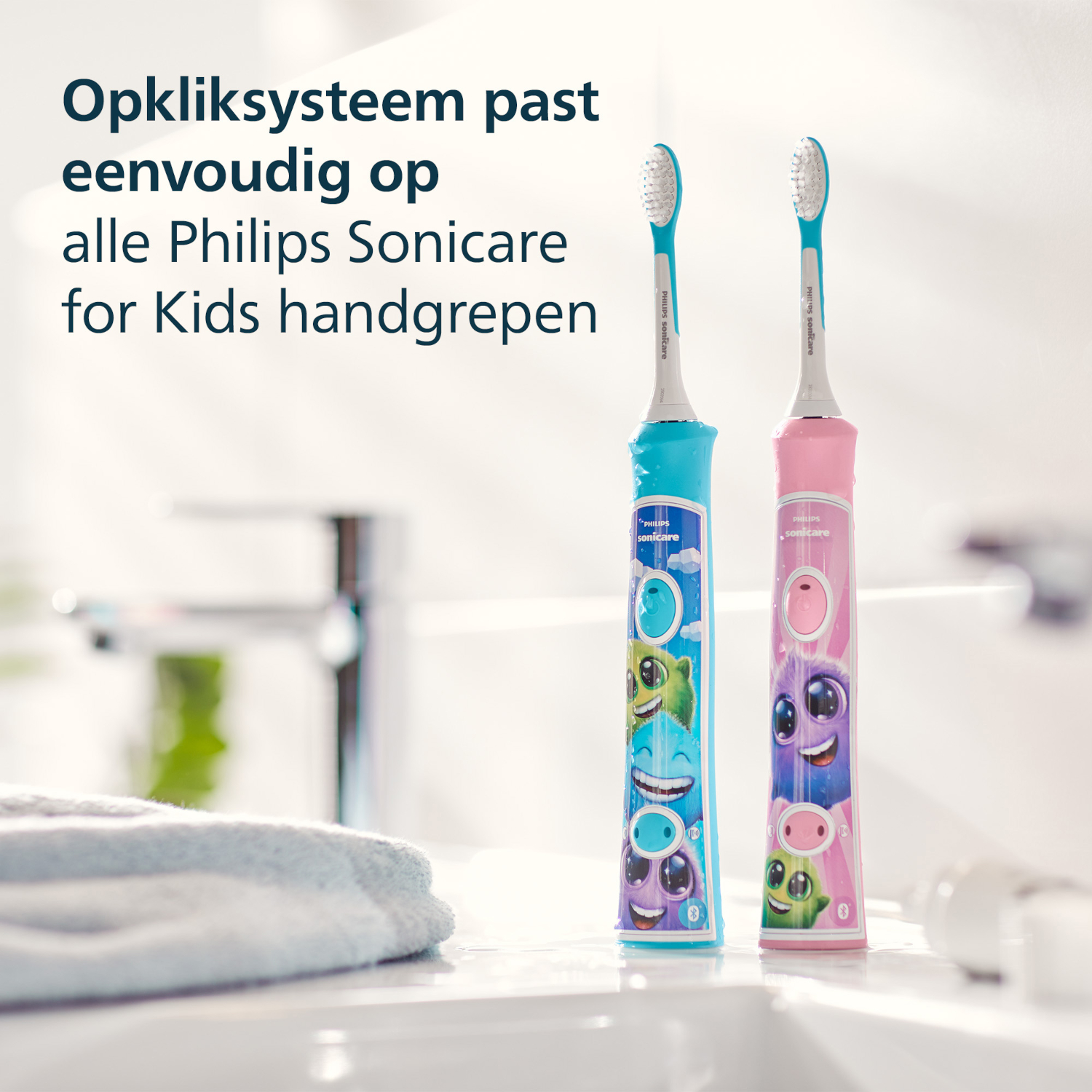Two colorful Philips Sonicare for Kids toothbrushes on a white sink. A blue and a pink one. Text above says 'Opkliksysteem'.