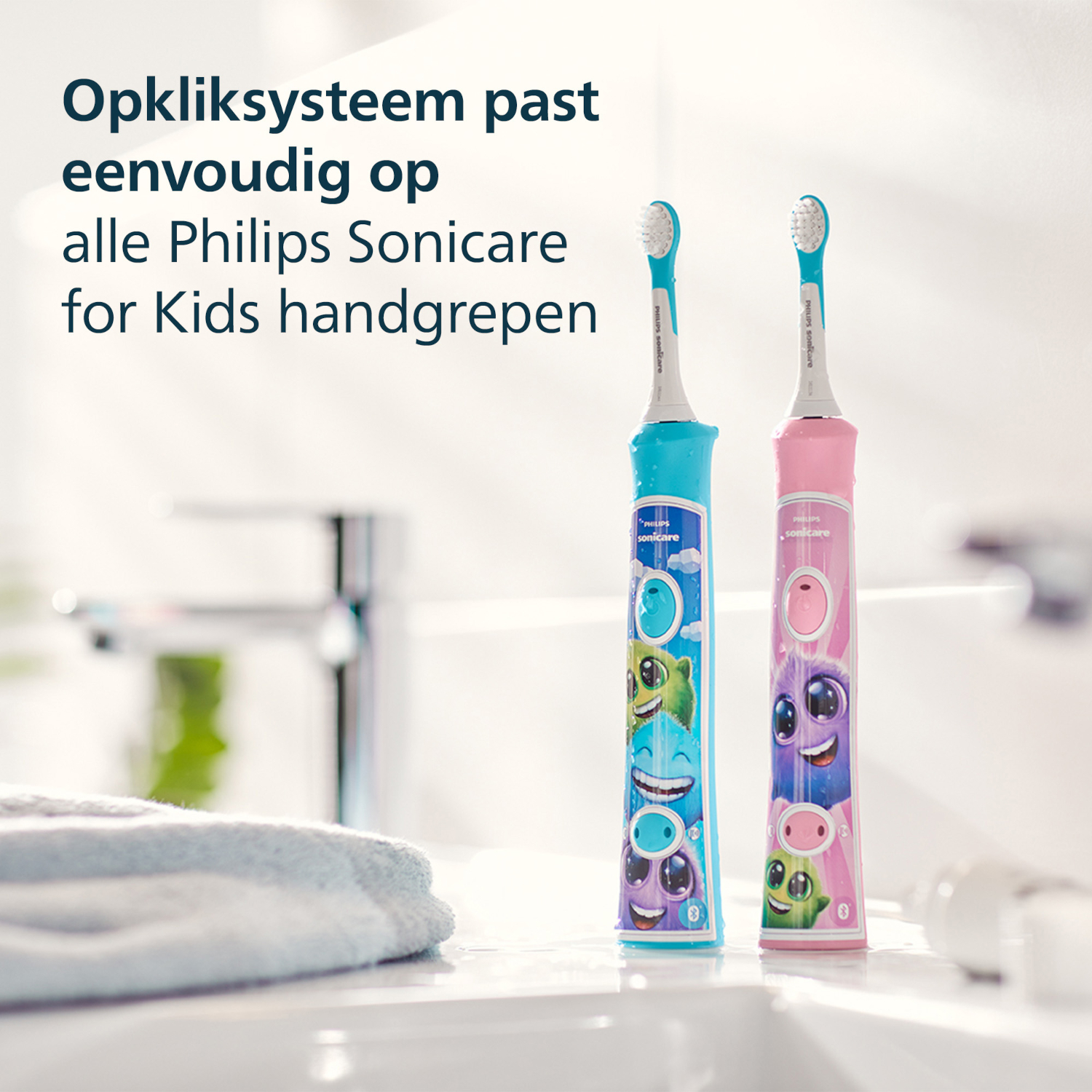 Two colorful Philips Sonicare for Kids toothbrushes stand upright. One is blue, the other pink, both with cartoon monster designs.