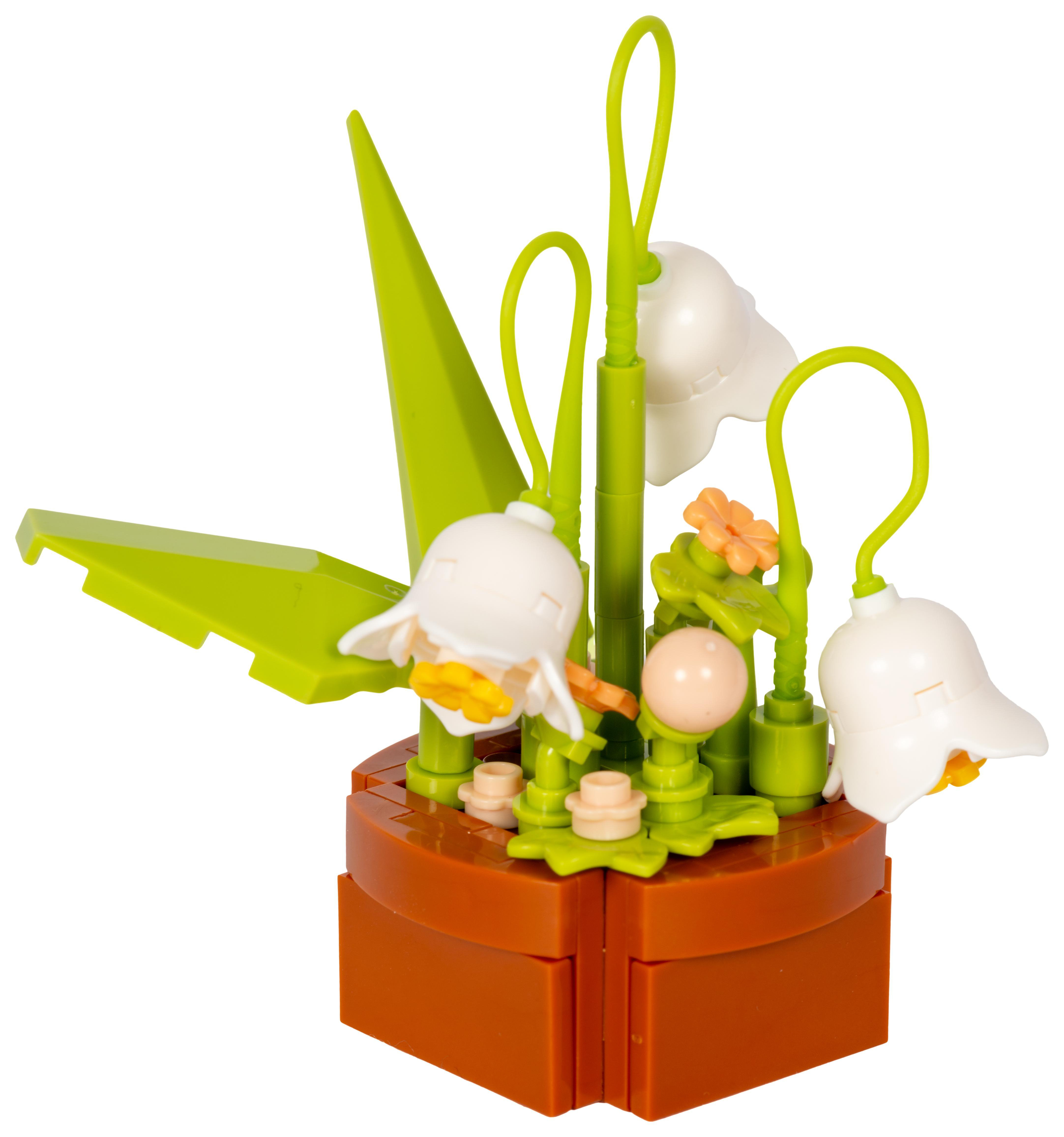 Ein Lego-Blumenarrangement in einem braunen Topf. Weiße Blumen und grüne Blätter heben sich vor weißem Hintergrund ab.
