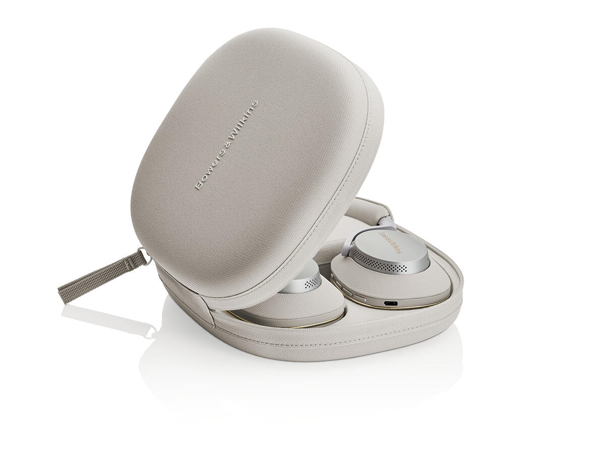 Nyitott bézs tok, benne fejhallgatóval. A fejhallgató ezüst és bézs színű, a tokon 'Bowers & Wilkins' felirat és egy pánt látható.
