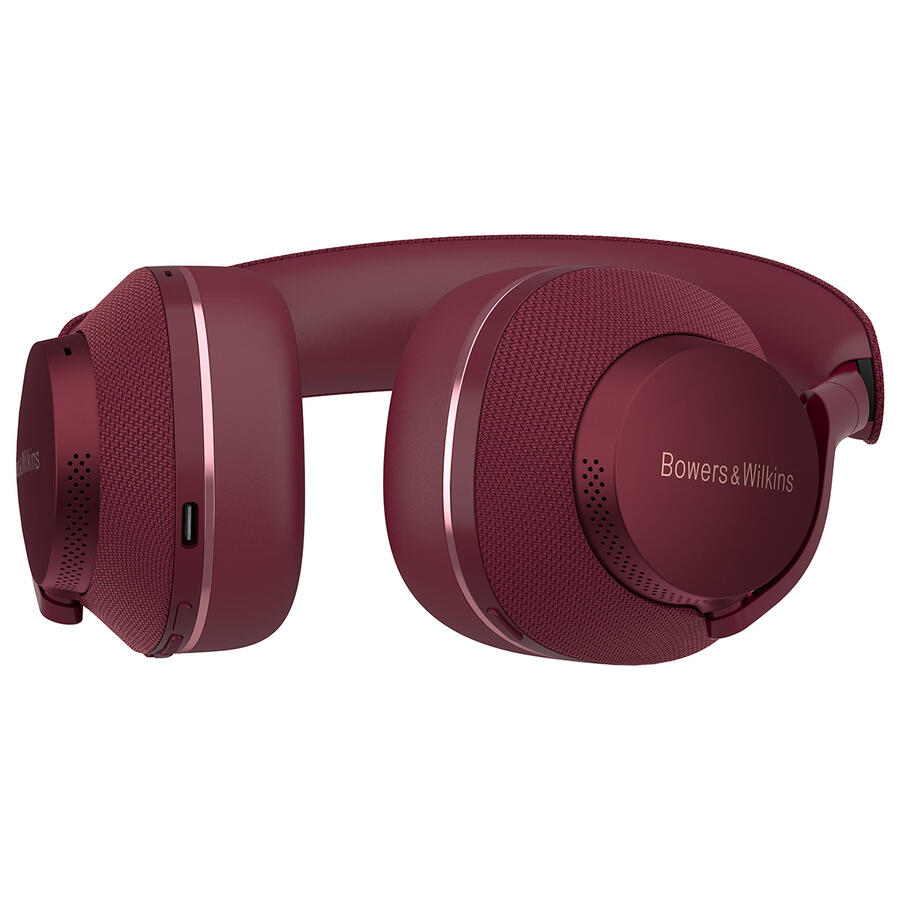 Fülre illeszkedő fejhallgató, bordó színű, Bowers & Wilkins logóval a fülkagylón, hálós textúrával a fülkagylókon, oldalsó porttal.