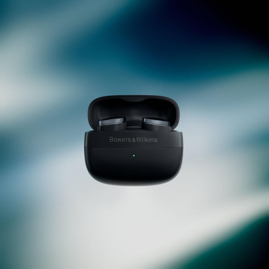 Fekete Bowers & Wilkins fülhallgatók egy nyitott töltőtokban, kék háttéren. A tokon zöld fény látható.