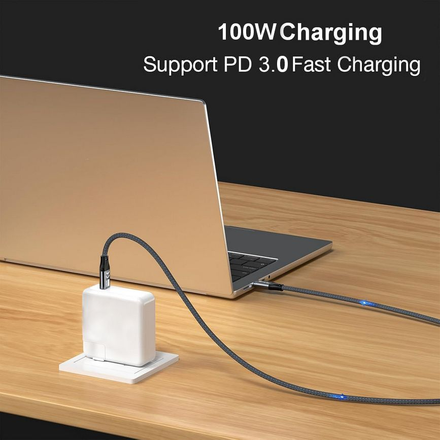 Laptop wird mit einem grauen Kabel geladen, ein weißes Netzteil auf weißer Basis. Der Hintergrund ist dunkel mit Text.