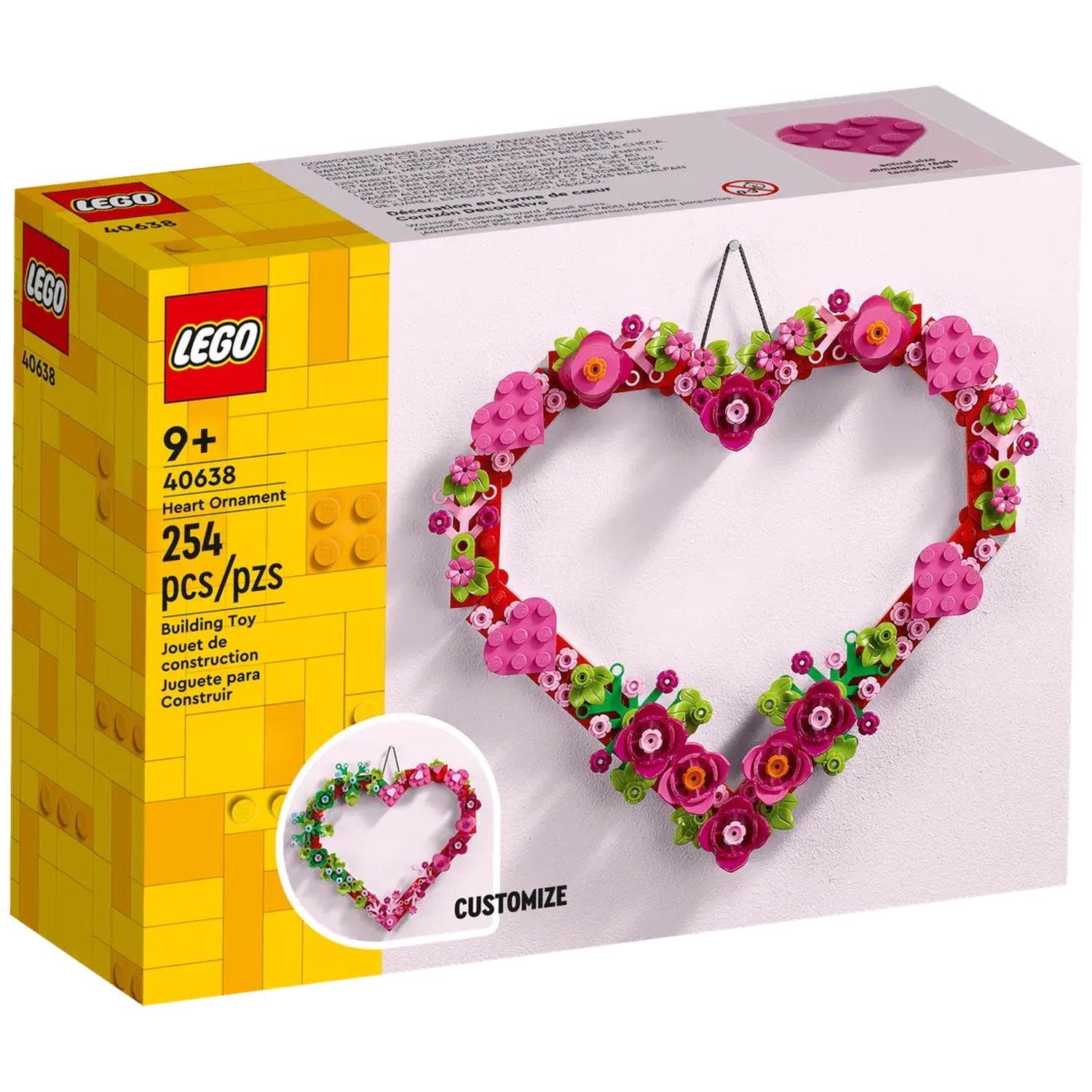 Une boîte d'ornement en forme de cœur Lego et l'ornement assemblé suspendu à un mur. Le cœur est décoré de fleurs.