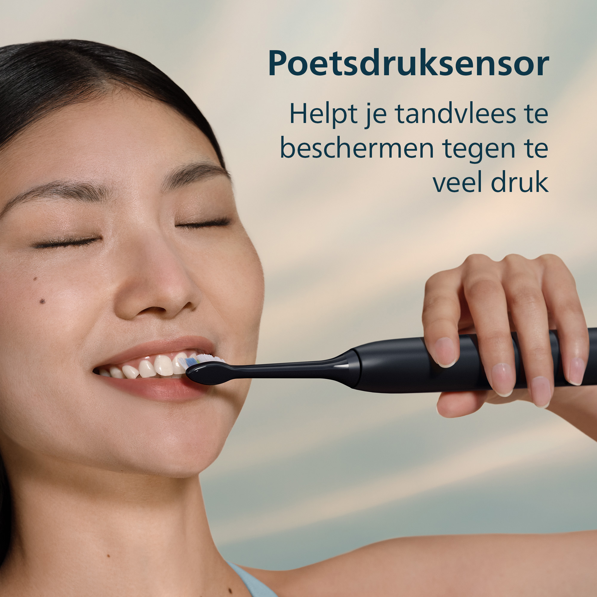 Een vrouw poetst haar tanden met een zwarte tandenborstel. Ze glimlacht met gesloten ogen. De achtergrond is lichtblauw en wit.