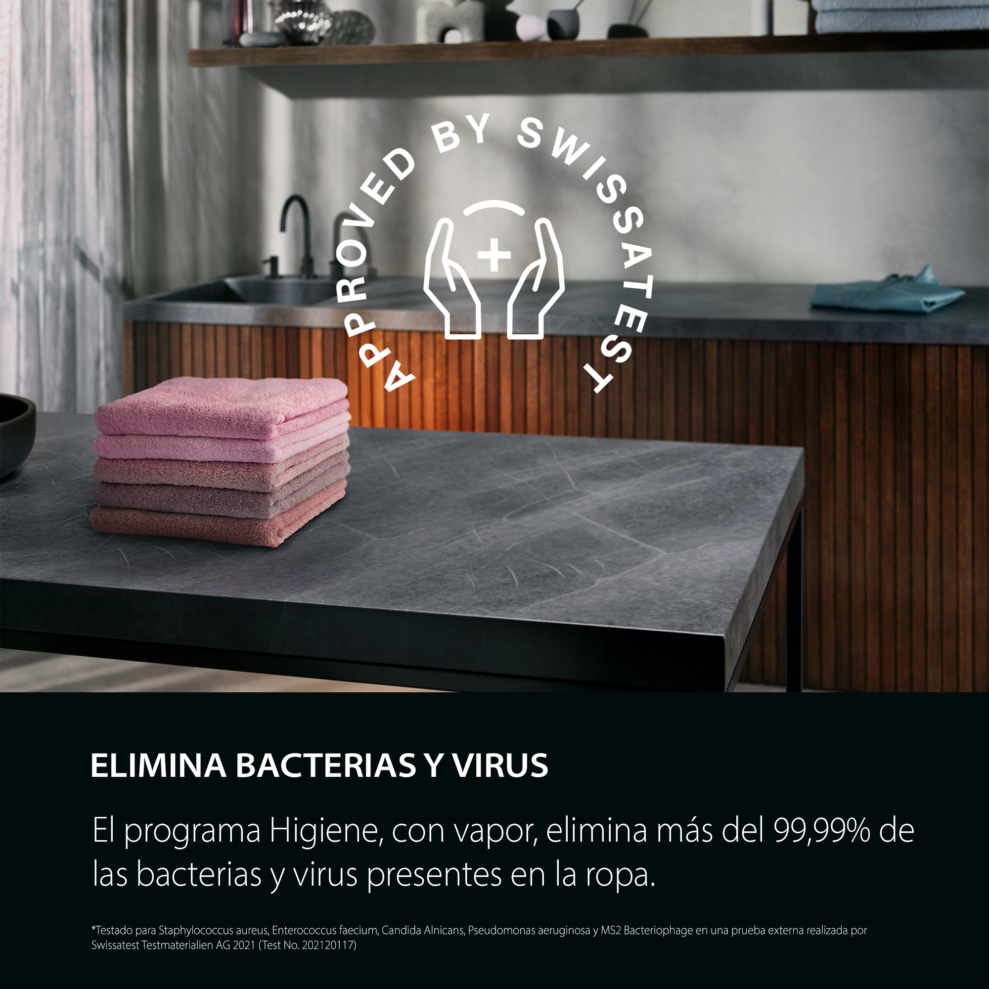 Pila de toallas rosas sobre superficie oscura. Fondo: lavabo y pared de madera. Texto: ELIMINA BACTERIAS Y VIRUS.
