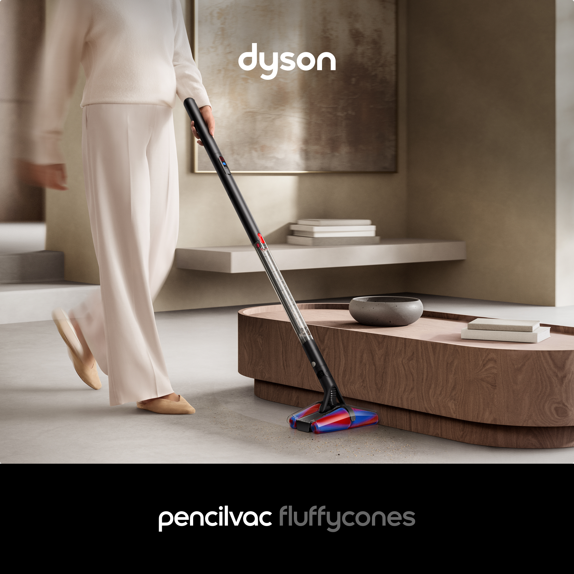 Eine Person saugt mit einem Dyson. Der Staubsauger ist unten rot und blau. Die Szene ist neutral mit einem Tisch.