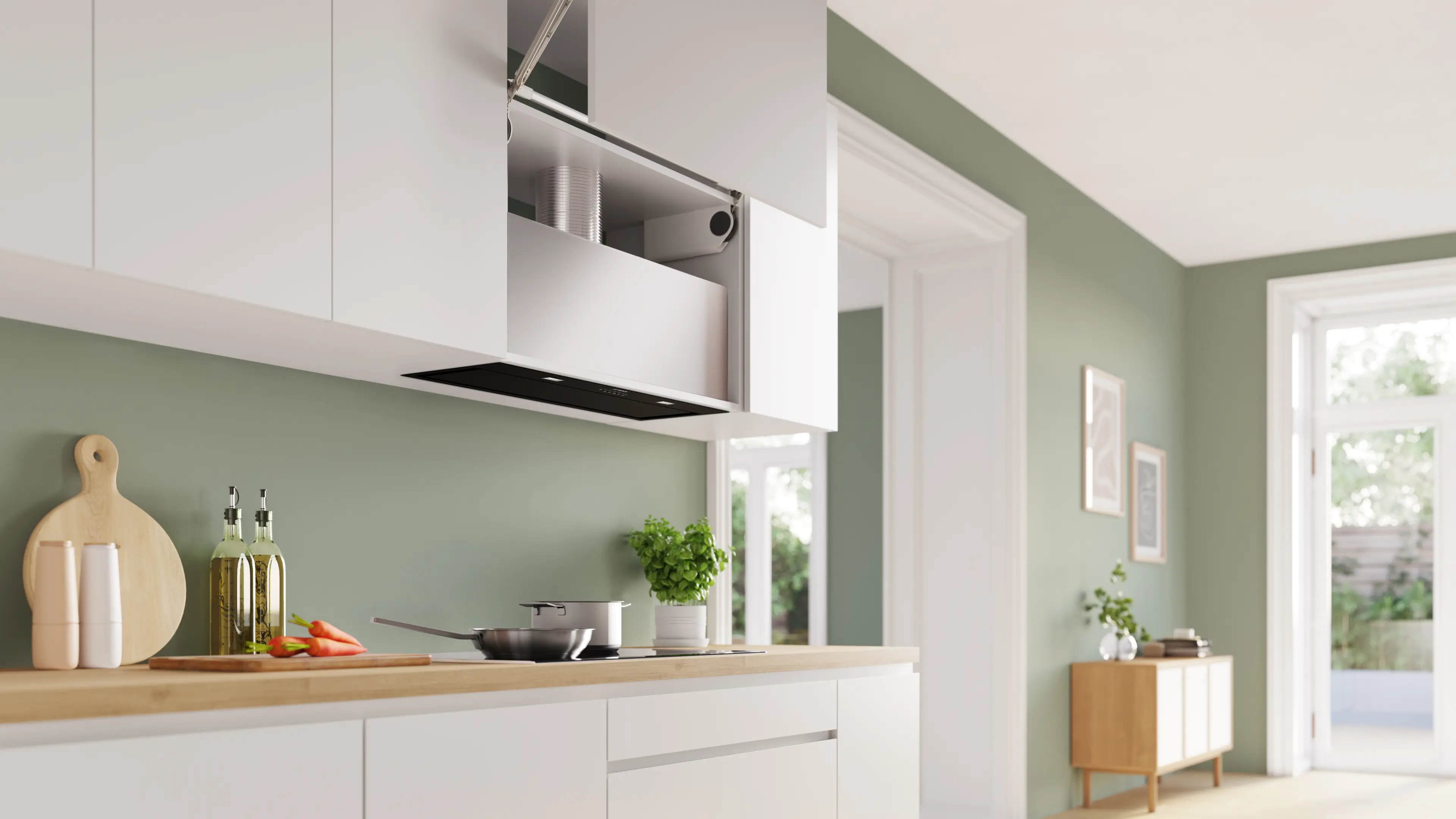 Cocina moderna con armarios blancos, encimera de madera y campana extractora. Verduras, botellas de aceite y una planta en la encimera.