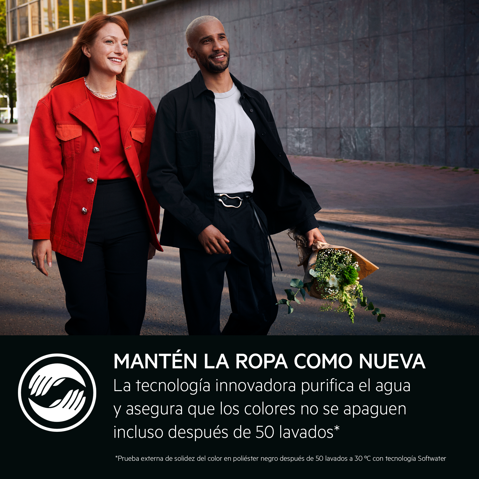 Una pareja caminando. La mujer viste de rojo, el hombre de negro. El hombre lleva flores. Fondo un edificio.