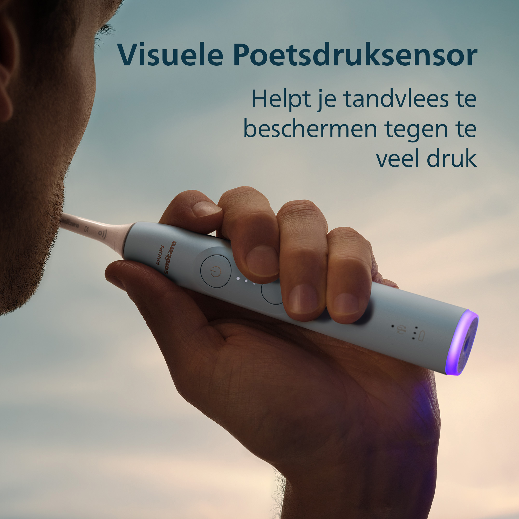 A person brushes teeth with a Philips Sonicare toothbrush. The brush has purple light and is held by a hand.