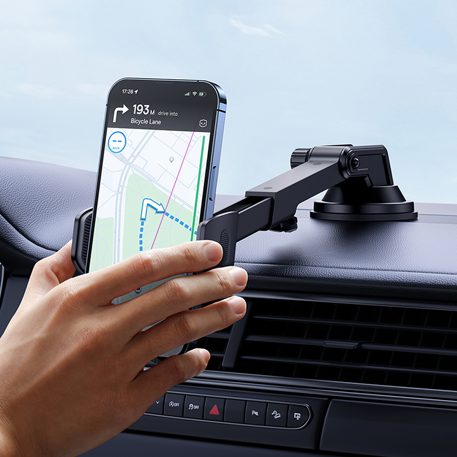 Una mano sostiene un teléfono en un soporte para automóvil. El teléfono muestra un mapa con indicaciones. Se ven un salpicadero y un soporte negros.