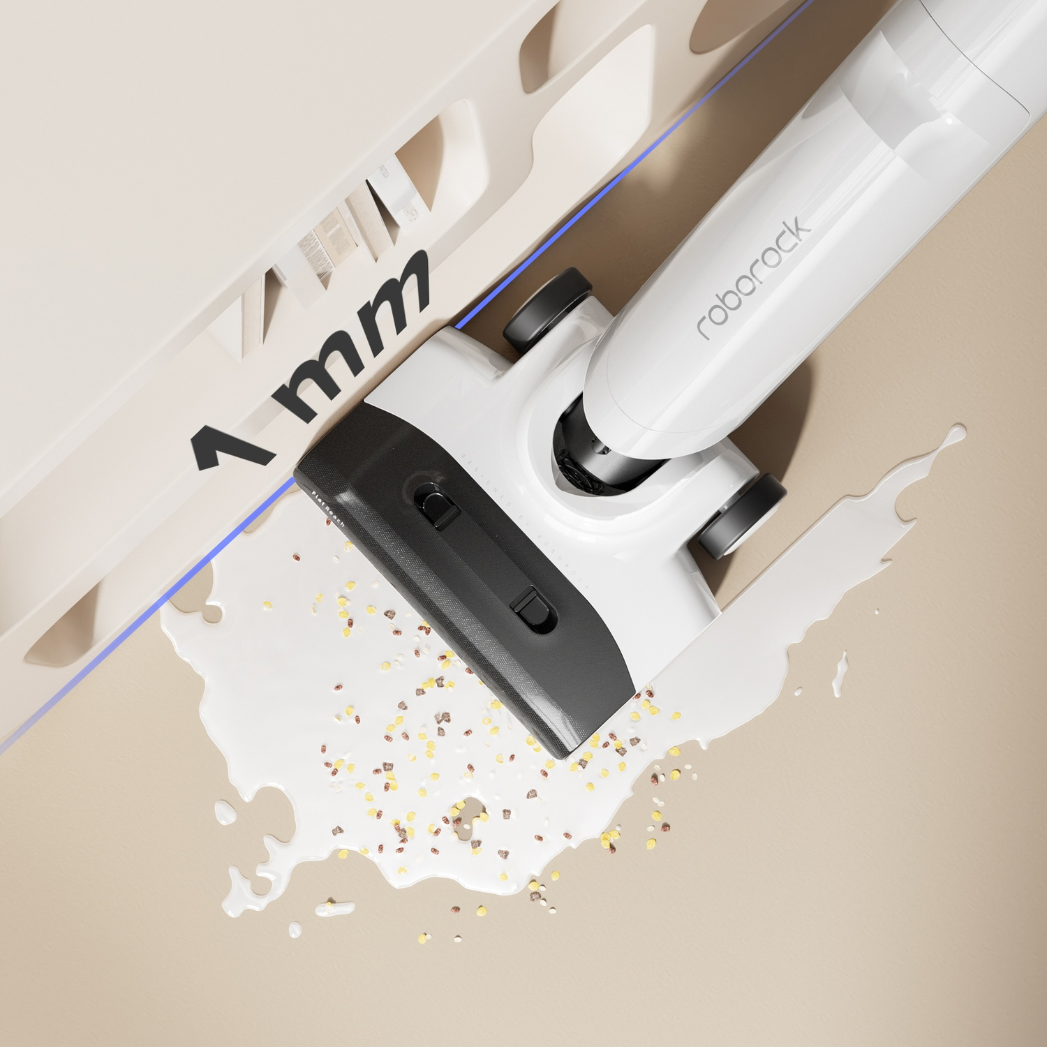 Un aspirapolvere Roborock bianco e nero pulisce una macchia con piccoli granuli su una superficie beige. Il testo '1 mm' è visibile.