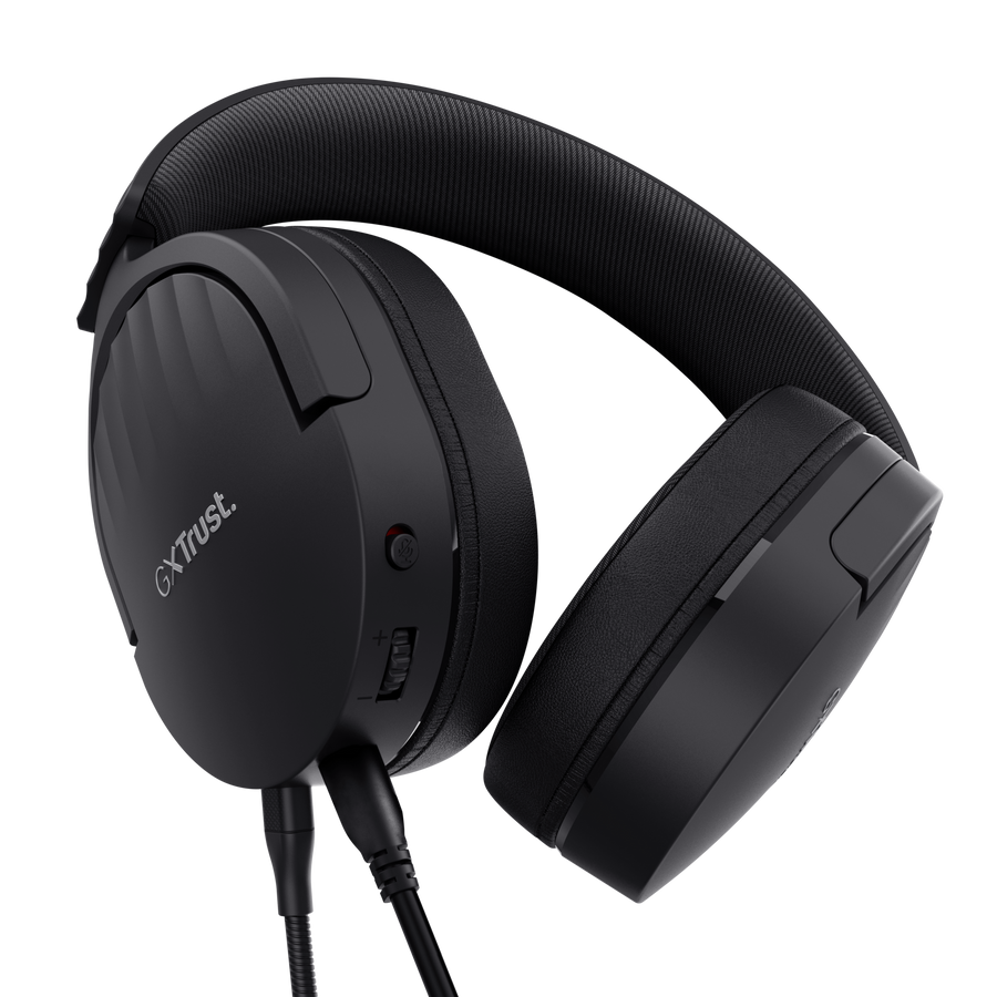 Auriculares negros Trust GX. Tiene una diadema y auriculares acolchados. Controles de volumen y micrófono visibles. Cable negro conectado.