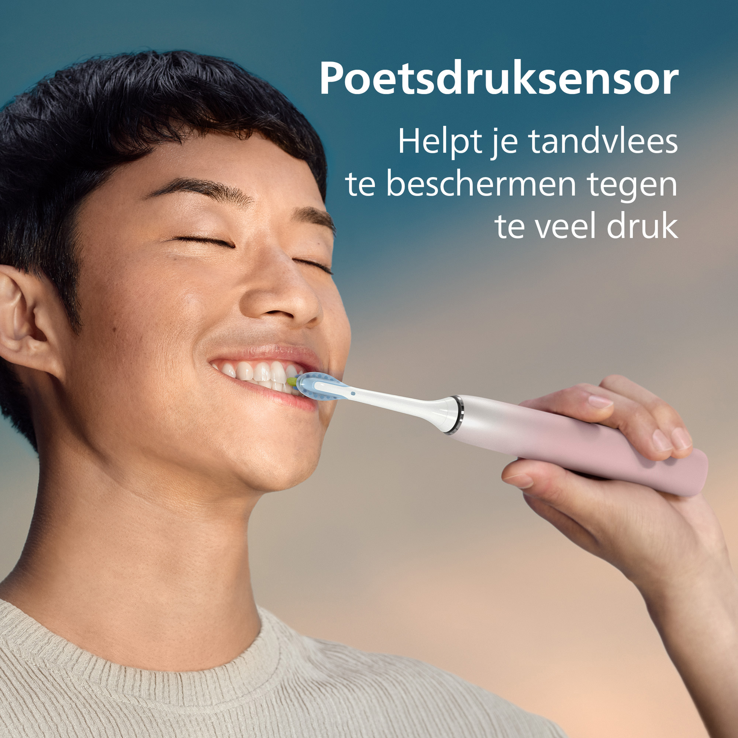 Een lachende man poetst zijn tanden met een roze elektrische tandenborstel. Tekst: Druksensor beschermt tandvlees tegen te veel druk.